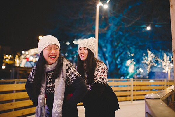 Two young girls ice skating during the holidays.